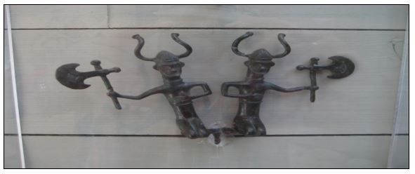 To bronsefigurer som viser et par knelende menn med bronseøkser og hjelmer med horn som gjør tegn med armene sine.  De har nok opprinnelig hørt til en større prosesjonsgruppe i sin samtid. Fra: Vitlycke museum, Tanum, Sverige. Foto: Heine Iversen.